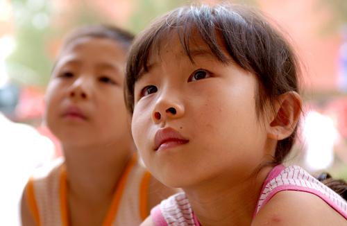 8月16日,在舟曲一中安置點(diǎn),9歲的奐榮(右)和6歲的弟弟奐立強(qiáng)正在戶外觀看電視節(jié)目。經(jīng)過各方努力,遭受特大山洪泥石流災(zāi)害的甘肅舟曲縣城已經(jīng)逐步恢復(fù)了供電供水。在舟曲縣城各災(zāi)區(qū)群眾安置點(diǎn),正在假期中的孩子們又可以通過當(dāng)?shù)卣块T設(shè)置在戶外的電視機(jī)看節(jié)目了。新華社記者 郭剛 攝