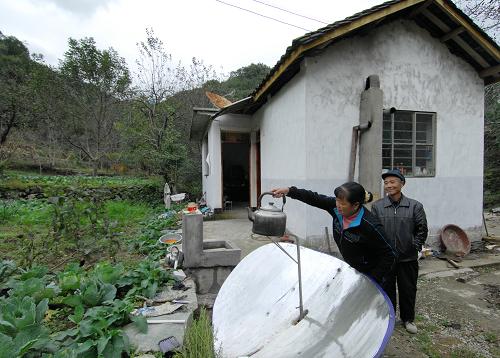 10月10日,甘肅康縣岸門口鎮(zhèn)牟家壩村村民唐彩云正在用太陽(yáng)能熱水器燒開(kāi)水。新華社記者 高健鈞 攝