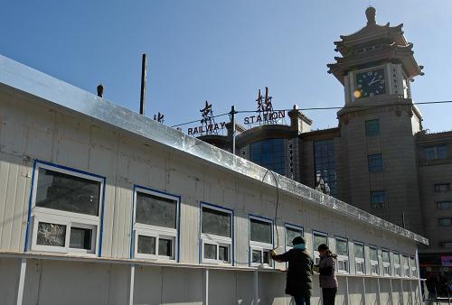 12月23日,工作人員在清潔北京火車站廣場(chǎng)西側(cè)搭建起的臨時(shí)售票窗口。新華社記者 張宇 攝