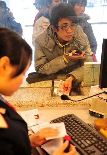 1月10日,旅客在武漢火車(chē)站排隊(duì)購(gòu)票,售票員在檢查其身份證件。新華社記者 郝同前 攝