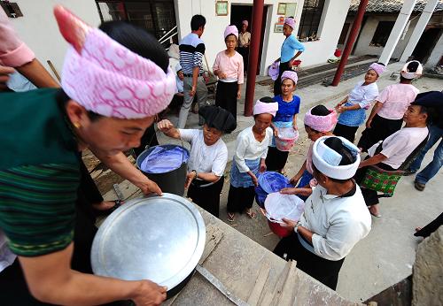 3月13日下午,傣族大媽們將做好的飯菜抬上拖拉機(jī),準(zhǔn)備送飯進(jìn)城。云南省盈江地震發(fā)生后,在盈江縣城最大的受災(zāi)群眾安置點盈湖公園旁,每天晚飯時分就有一群傣族大媽坐拖拉機(jī)為災(zāi)區(qū)群眾送上熱氣騰騰的傣家飯菜。這群傣族婦女來自盈江縣舊城鎮(zhèn)東丙村奪公寨,寨子距離盈江縣城大概15公里,受災(zāi)情況不算很嚴(yán)重。當(dāng)寨子里老人協(xié)會婦女小組的成員得知其他地方的災(zāi)情后,決定為受災(zāi)的鄉(xiāng)親們做一些力所能及的事。她們動員全寨每戶出錢10元至50元不等,籌到捐款近千元買菜買水買米,烹制出美味的傣家家常飯,送到城里安置點免費發(fā)放給受災(zāi)群眾。傣族大媽們燒制的愛心傣家飯溫暖著受災(zāi)群眾的心。新華社記者 秦晴 攝
