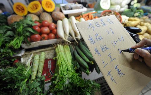 6月14日,在合肥一農貿市場,一名蔬菜零售商在登記當天幾種蔬菜的零售價格。新華社記者 劉軍喜 攝