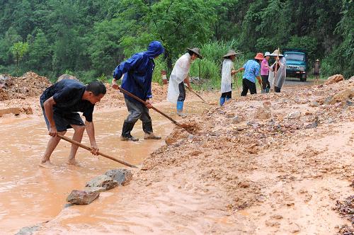 6月15日,在通往廣西羅城納翁鄉(xiāng)的公路上,當(dāng)?shù)厝罕娫谇謇硭降穆访妗?新華社發(fā)(吳耀榮 攝)