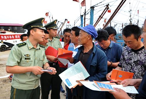 6月16日,秦皇島市洋河口邊防派出所民警林文昌(左)在漁船碼頭向漁民宣傳有關(guān)休漁期的新規(guī)定。新華社記者 楊世堯 攝