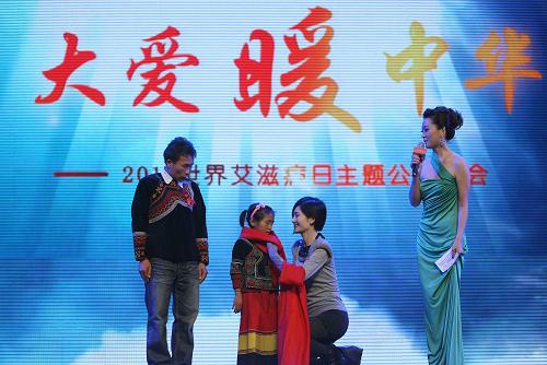 11月30日,嘉賓謝娜(右二)為來(lái)自四川大涼山的艾滋孤兒小吉克(左二)戴上紅圍巾。當(dāng)日,在第24個(gè)世界艾滋病日到來(lái)之際,由全國(guó)工商聯(lián)和國(guó)務(wù)院防治艾滋病工作委員會(huì)辦公室主辦的“大愛(ài)暖中華”世界艾滋病日主題公益晚會(huì)在北京舉行。新華社發(fā)(李方宇 攝)
