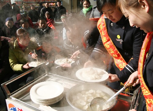 1月30日,濟(jì)南長(zhǎng)途客運(yùn)中心站的工作人員為準(zhǔn)備乘車返鄉(xiāng)的農(nóng)民工送水餃。新華社發(fā)(呂傳泉 攝)