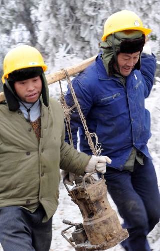 1月31日,在貴陽市水口寺的一條因雪凝災害造成的220千伏安輸電線路損毀現(xiàn)場,南方電網(wǎng)公司貴州送變電的兩名搶險人員正在運送搶修設備。 新華社記者 楊楹 攝