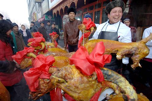 2008年12月8日,在烏魯木齊市二道橋愛(ài)國(guó)巷,來(lái)自庫(kù)車的艾合買提江在向顧客介紹自己烤制的特色烤全羊。每年的“古爾邦節(jié)”,烏魯木齊市的穆斯林群眾以傳統(tǒng)而獨(dú)特的方式歡度佳節(jié)。 新華社發(fā)(楊萬(wàn)江攝)