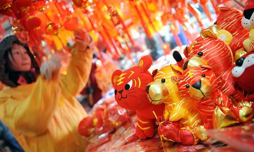 1月12日,南昌市西湖區(qū)萬壽宮商城一家店鋪工作人員擺出新年飾物。近日,南昌市年味漸濃,各大商場、街道被節(jié)日飾品裝扮一新,“虎”圖案貼畫、生肖虎等春節(jié)飾物銷售紅火,各種燈籠、年畫、剪紙等傳統(tǒng)年貨受到市民歡迎。新華社記者 周科 攝