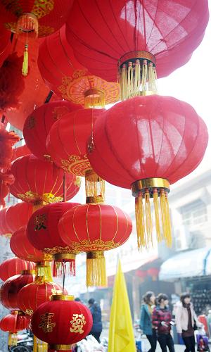 1月12日,幾位市民從南昌市中山路一家掛滿大紅燈籠的店鋪前走過。新華社記者 周科 攝