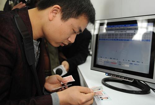 1月21日,一名旅客在深圳火車北站購票窗口核實(shí)自己買到的實(shí)名制火車票。新華社記者 盧漢欣 攝