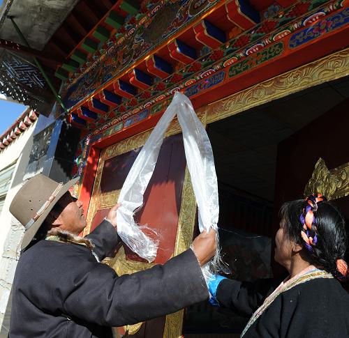 1月20日,西藏堆龍德慶縣乃瓊鎮(zhèn)農(nóng)民倫珠旺杰(左)在自家的安居新房門上掛哈達。4年來該縣已有5934戶、25400余農(nóng)牧民住上了安居新房。