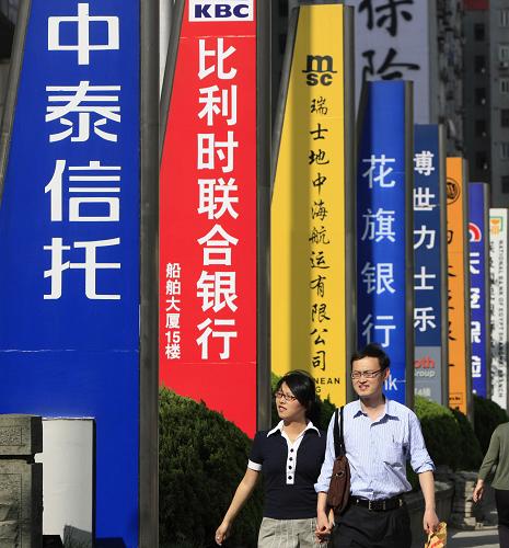 兩位行人從上海浦東陸家嘴金融貿(mào)易區(qū)內(nèi)林立的廣告牌旁走過(2009年6月9日攝)。新華社發(fā)(資料照片)