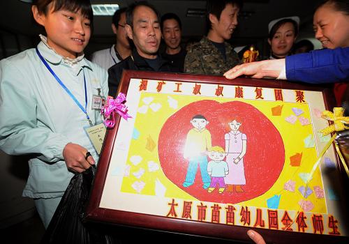 4月16日,在山西醫(yī)科大學(xué)第二醫(yī)院,太原市一家幼兒園的小朋友向出院的礦工送上寫有“祝礦工叔叔康復(fù)團聚”的手工畫。新華社記者 燕雁 攝