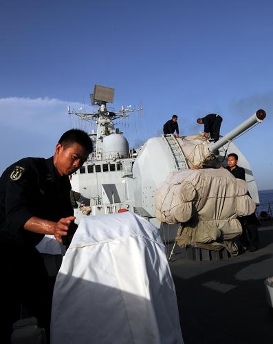 5月16日,“廣州”艦戰(zhàn)士為裝備套上防護(hù)外罩。新華社記者 劉春暉 攝