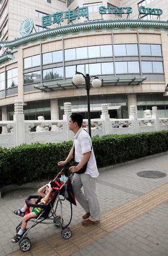 7月9日,一名市民推著童車從位于北京的國家電網(wǎng)大樓前走過。新華社記者 王建華 攝