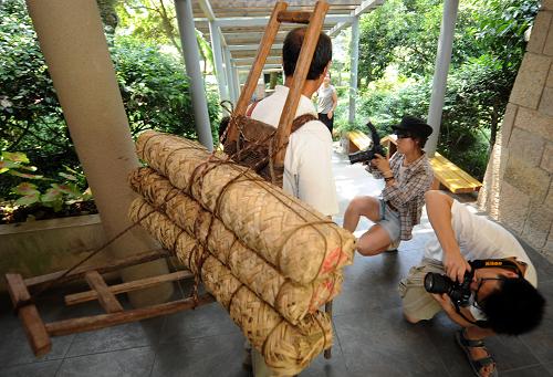 7月22日,一名工作人員用川藏茶馬古道背夫的背夾子背起茶包,走向中國茶葉博物館陳列室。新華社記者 韓傳號 攝
