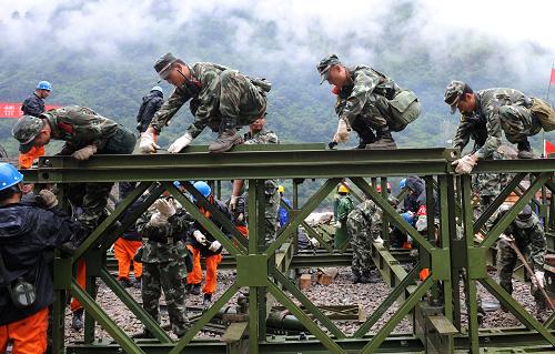 8月23日,武警官兵和公路部門的工作人員在加緊架設(shè)鋼架橋。新華社記者 藺以光 攝