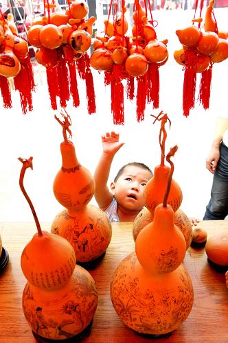 9月12日,聊城葫蘆文化節(jié)上展出的葫蘆藝術(shù)品吸引了一名小朋友的目光。新華社發(fā)(張憲舉 攝)