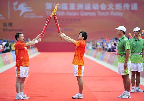 10月20日,亞運(yùn)會(huì)火炬?zhèn)鬟f汕尾站第一棒火炬手吳武棠(左二)與第二棒火炬手卓志強(qiáng)(左一)進(jìn)行交接。新華社記者 梁旭 攝