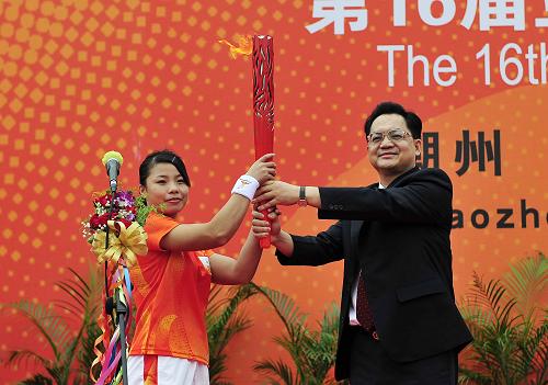 10月22日,第一棒火炬手張宛瓊(左)從潮州市委書記駱文智手中接過(guò)火炬。新華社記者 梁旭 攝