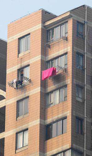 12月20日,回搬居民在上海膠州路失火大樓相鄰大樓陽臺上晾曬衣服。從當(dāng)日起,上海“11·15”特大火災(zāi)事故中相鄰兩幢未著火大樓居民開始回搬。經(jīng)過對該兩幢大樓房屋結(jié)構(gòu)安全、水質(zhì)等項目進行檢測,相關(guān)指標均符合安全標準,兩幢大樓用電、煤氣、電話等公用設(shè)施已恢復(fù)正常。新華社發(fā)