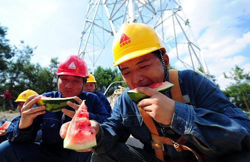 7月4日,在安徽省池州市里山鄉(xiāng)的220千伏楓觀線工地,安徽送變電工程公司的施工人員在鐵塔下吃西瓜解暑。新華社發(fā)(鄭賢列 攝)