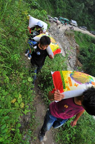 7月12日,由于道路損毀,隊(duì)員們用肩膀?qū)⒕葷?jì)糧扛進(jìn)村子。遭受特大暴雨襲擊以來,一支由黨員干部帶頭、群眾自發(fā)參與的“抗洪別動(dòng)隊(duì)”活躍在貴州省道真仡佬族苗族自治縣玉溪鎮(zhèn)大路村。災(zāi)害發(fā)生后,大陸村大路組組長、共產(chǎn)黨員周德興帶領(lǐng)16位村民組成“抗洪救災(zāi)自愿服務(wù)隊(duì)”,用自家的摩托車、汽車為受災(zāi)村民送去救濟(jì)糧、棉被、衣物,為村民打開通往村外的道路。截至目前,他們已為村民送去救濟(jì)糧2000多斤、開辟山路數(shù)百米。新華社記者 劉續(xù) 攝