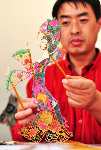 在廣西南寧國際會展中心,一名皮影藝人在演示皮影技藝(11月2日攝)??偛课挥诎屠璧穆?lián)合國教科文組織11月27日宣布,正在印度尼西亞巴厘島舉行的保護(hù)非物質(zhì)文化遺產(chǎn)政府間委員會第6屆會議已決定,把中國皮影戲列入“人類非物質(zhì)文化遺產(chǎn)代表作名錄”。中國皮影戲是一種以皮制或紙制的彩色影偶形象,伴隨音樂和唱腔表演故事的戲劇形式。皮影藝人在幕后用木桿操控影偶,通過光線照射在半透明的幕布上創(chuàng)造出動態(tài)的形象。皮影藝人有許多絕技,諸如即興演唱、假聲扮演,一個人同時操縱數(shù)個影偶,以及能夠演奏多種不同的樂器。新華社發(fā)(陸波岸 攝)