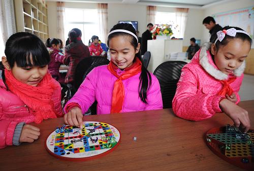 1月16日,重慶市九龍坡區(qū)西彭鎮(zhèn)第三小學(xué)的趙藝(中)與同學(xué)在東林村“留守兒童幸福家園”下跳棋。新華社記者 李健 攝