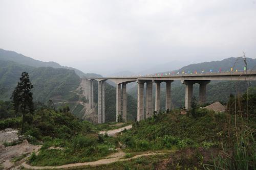 崇山峻嶺中的臘八斤特大橋全貌(4月27日攝)。4月28日,雅西高速全線建成通車,當(dāng)車輛行走在200多米高的臘八斤特大橋面上時,如同在云霧中徜徉。臘八斤特大橋位于四川省滎經(jīng)縣石滓鄉(xiāng)境內(nèi),全長1106米,該橋高230米,最高橋墩(10號橋墩)高182.6米。這里地形陡峭,巖層硬度低,降雨量大,地質(zhì)環(huán)境復(fù)雜,施工單位建設(shè)橋梁時首創(chuàng)了“鋼管疊合柱”橋墩、C80號混凝土自密實澆筑工藝。它的建成為我國西部山區(qū)復(fù)雜地形條件下高速公路橋梁建設(shè)作出了有益嘗試。新華社記者 江宏景 攝