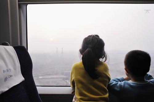 列車駛?cè)牒幽暇硟?nèi),夕陽(yáng)西下,兩個(gè)孩子看著窗外風(fēng)景入了迷(1月18日攝)。 新華社記者 梁旭 攝