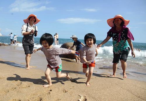 家長(zhǎng)帶孩子在海南省三亞市南山景區(qū)海邊游玩(2月15日攝)。新華社發(fā)(陳文武 攝)
