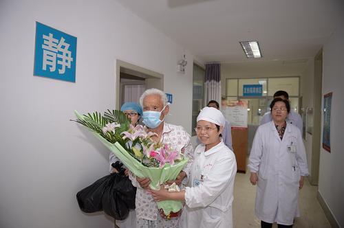 5月8日,醫(yī)護人員給患者熊某送上鮮花,并攙扶他走出病房。新華社記者 周密 攝