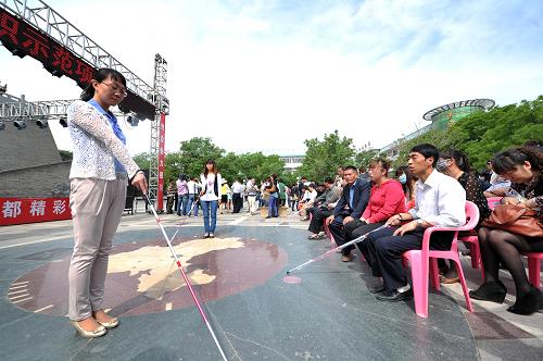 5月14日,在寧夏銀川市玉皇閣廣場上,銀川市殘疾人聯(lián)合會(huì)的工作人員通過聲音示范向盲人介紹盲杖的使用方法。新華社記者 彭昭之 攝