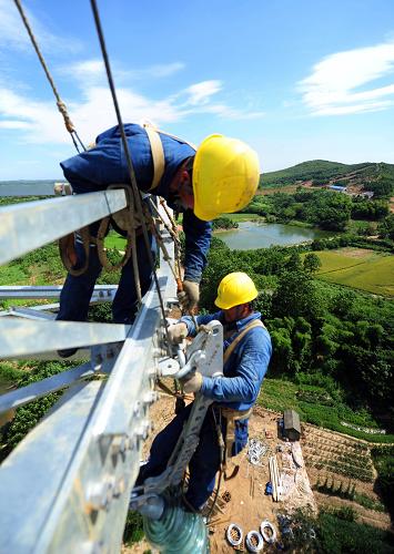 7月18日,在安徽省宣城市宣州區(qū)古泉鎮(zhèn)境內(nèi),電力工人冒著高溫在60多米高的輸電鐵塔上施工。新華社發(fā)(鄭賢列 攝)