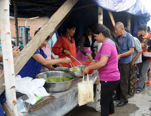 8月15日,被安置在常勝鄉(xiāng)江南村的村民在領取食物。新華社記者 梁書斌 攝