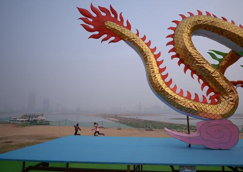 1月27日,在南昌市紅谷灘新區(qū)的贛江江灘上,兩個孩子從一個龍形花燈旁跑過。新華社記者 周密 攝