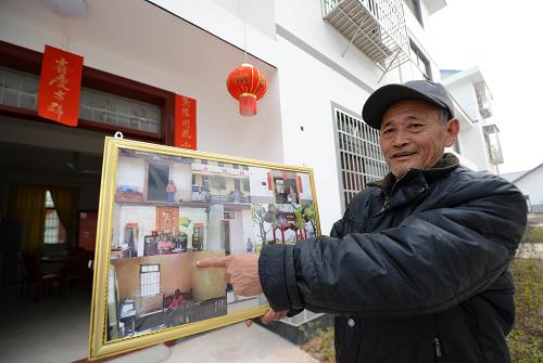 贛州市興國(guó)縣埠頭鄉(xiāng)楓林村66歲的村民胡世瑞在新居前介紹自己曾經(jīng)住過的土坯房(1月27日攝)。新華社記者 周科 攝
