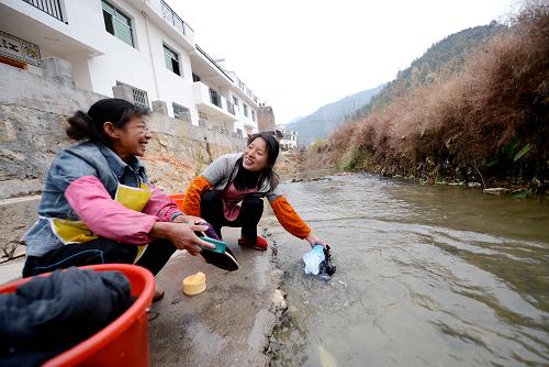 贛州市上猶縣水巖鄉(xiāng)古田村村民在改造后的新居前的小河邊洗衣服(1月26日攝)。新華社記者 周科 攝