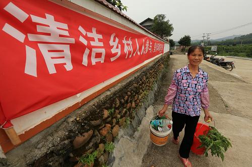 6月4日,在廣西柳州市融安縣大將鎮(zhèn)大潭屯,一名村民將分類好的垃圾送往收集點(diǎn)。新華社發(fā)(譚凱興 攝)