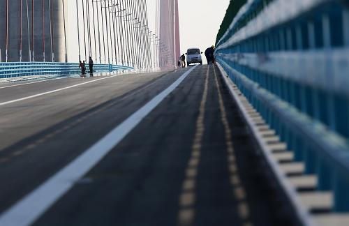10月10日,工人們?cè)诰沤L(zhǎng)江公路大橋橋面上進(jìn)行通車(chē)前的后期收尾工作。新華社發(fā)(張海巖 攝)