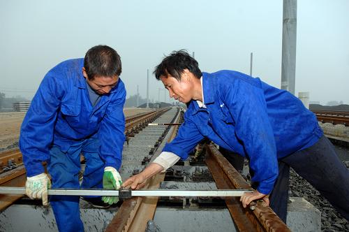 10月2日,在京滬高鐵濟(jì)南西客站建設(shè)現(xiàn)場(chǎng),來(lái)自中國(guó)鐵建十六局集團(tuán)的彭水糧(左)和蔣益遙在精準(zhǔn)調(diào)整軌道。新華社記者 郭緒雷 攝