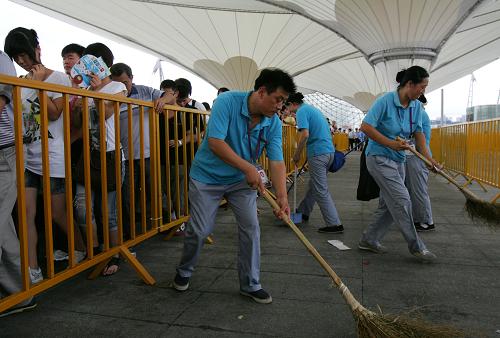 8月31日,在世博園6號(hào)門外,幾名“小蜜蜂”保潔員趕在下一批游客進(jìn)入排隊(duì)通道前清掃地面上遺留的雜物。新華社記者 孟晨光 攝
