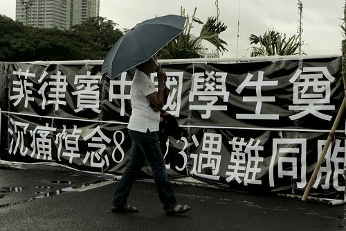 8月31日,在菲律賓首都馬尼拉,一名菲律賓人走過(guò)劫持人質(zhì)事件悼念活動(dòng)的條幅。新華社發(fā)(法布里加爾 攝)