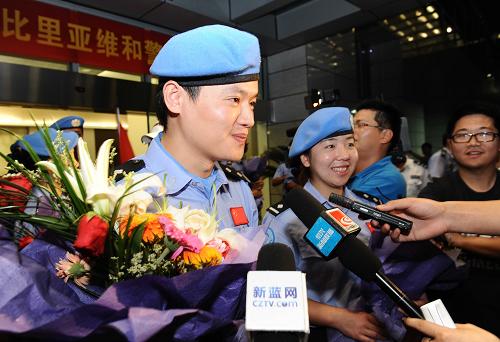 8月1日晚,從利比里亞完成任務歸國的中國維和警察劉英(左二)與趙鑫國(左一)在杭州蕭山國際機場接受媒體采訪。新華社發(fā)(袁云 攝)