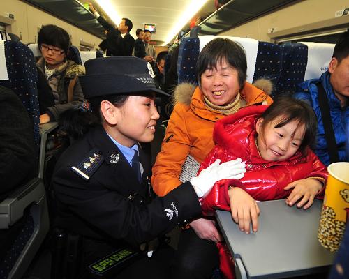 1月8日,乘警李娜(左一)在高鐵動(dòng)車上對(duì)帶孩子的乘客進(jìn)行安全提示。新華社記者 程敏 攝