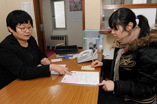 3月18日,中國駐札幌總領(lǐng)事館工作人員為護照過期的巖手大學(xué)中國留學(xué)生吳迪(右)補辦回國手續(xù)。 日本大地震發(fā)生后,負責日本一道(北海道)三縣(巖手、青森、秋田)的中國駐札幌總領(lǐng)事館立即啟動應(yīng)急機制,除日常領(lǐng)事業(yè)務(wù)外,派出前方工作組到重災(zāi)區(qū)巖手縣慰問、搜尋中國公民,后方24小時開通熱線,收集、發(fā)布中國公民平安信息,全力投入所轄的中國公民在日本的轉(zhuǎn)移工作。 新華社記者宋振平攝