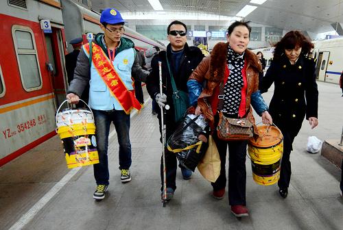 1月16日,在濟(jì)南火車站,車站青年志愿者協(xié)助身有殘疾的旅客乘車。 當(dāng)日,2014年春運(yùn)正式開始。 新華社發(fā)(趙曉明 攝)