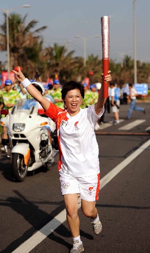 5月6日,奧運火炬手王麗芳手持火炬?zhèn)鬟f。當(dāng)日,北京奧運圣火傳遞活動在海南省??谑信e行。 新華社記者 邢廣利 攝